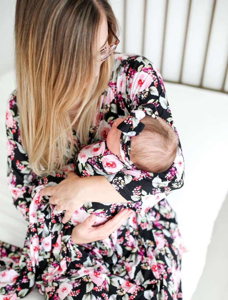 Mother holding baby wrapped in a swaddle with matching outfits