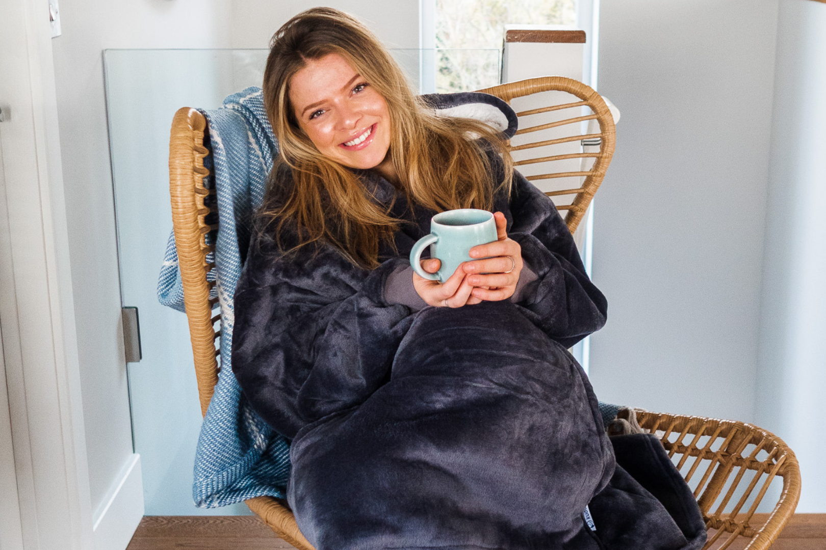 Woman wearing hoodie blanket holding a mug