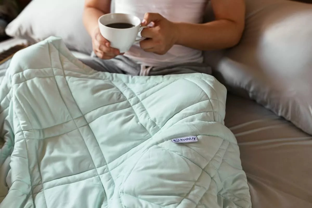 Person using cooling weighted blanket holding a mug