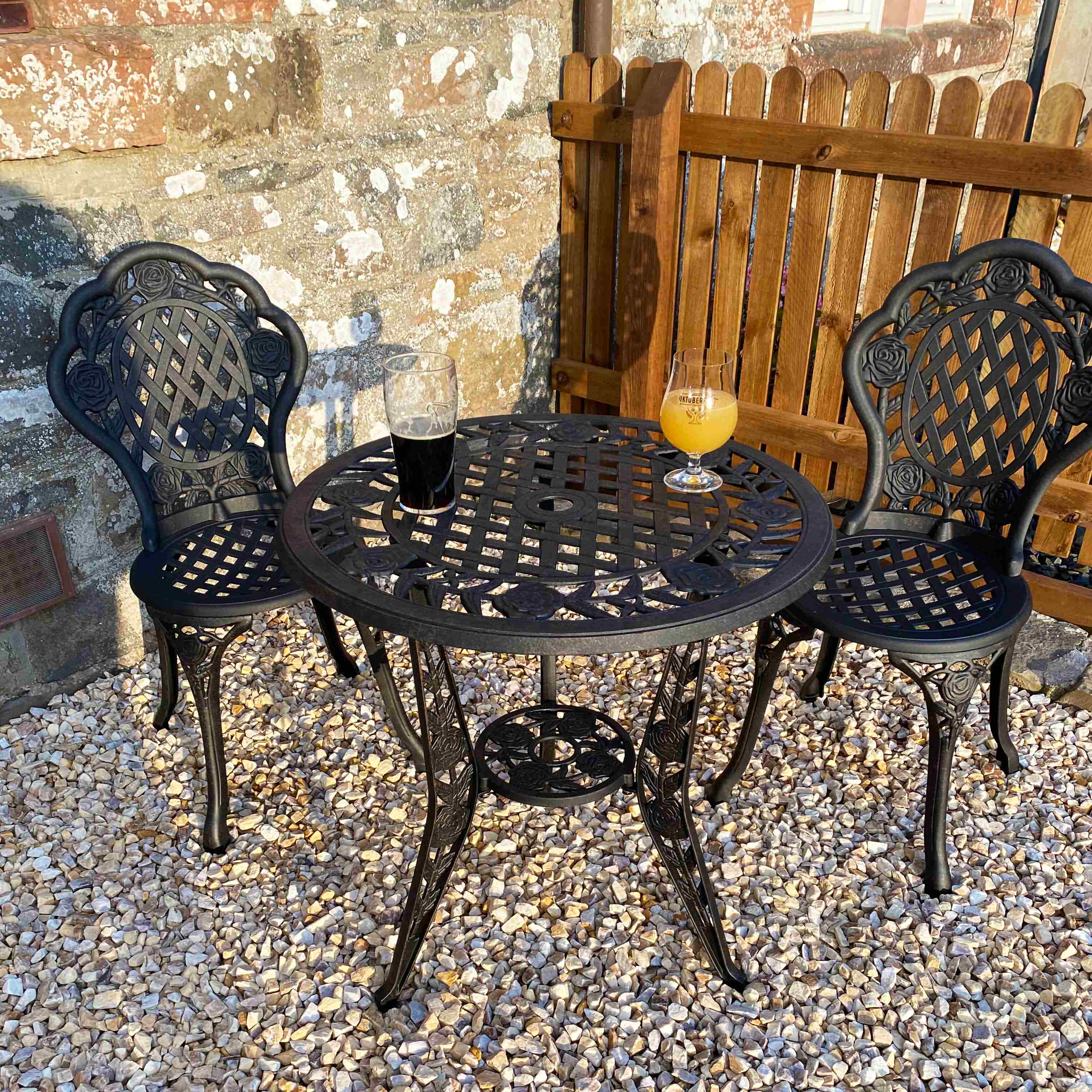 Rustikaler Aluminiumtisch mit blauen Sitzkissen und Steindekoration im Garten]