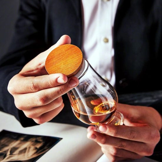 Man in suit holding a Glencairn glass with topper and whiskey