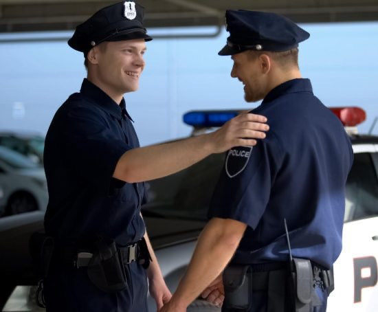 Two young police officers standing near squad car