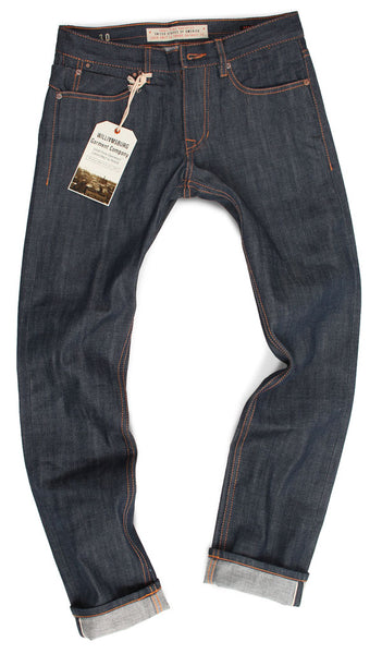 A flat photo on a white background of Williamsburg Garment Company's Grand Street slim-fit selvedge raw denim jeans from 2013. These jeans helped the business quickly soar to the top of the denim market, earning designer Maurice Malone the nickname "Steve Jobs of Denim" by Brooklyn Magazine and other media, as well as being named one of the "Best Raw Denim Jeans Brands" in 2013.