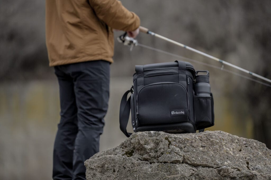 Drifter 12 sitting on rock with man holding a spinning rod fishing in background