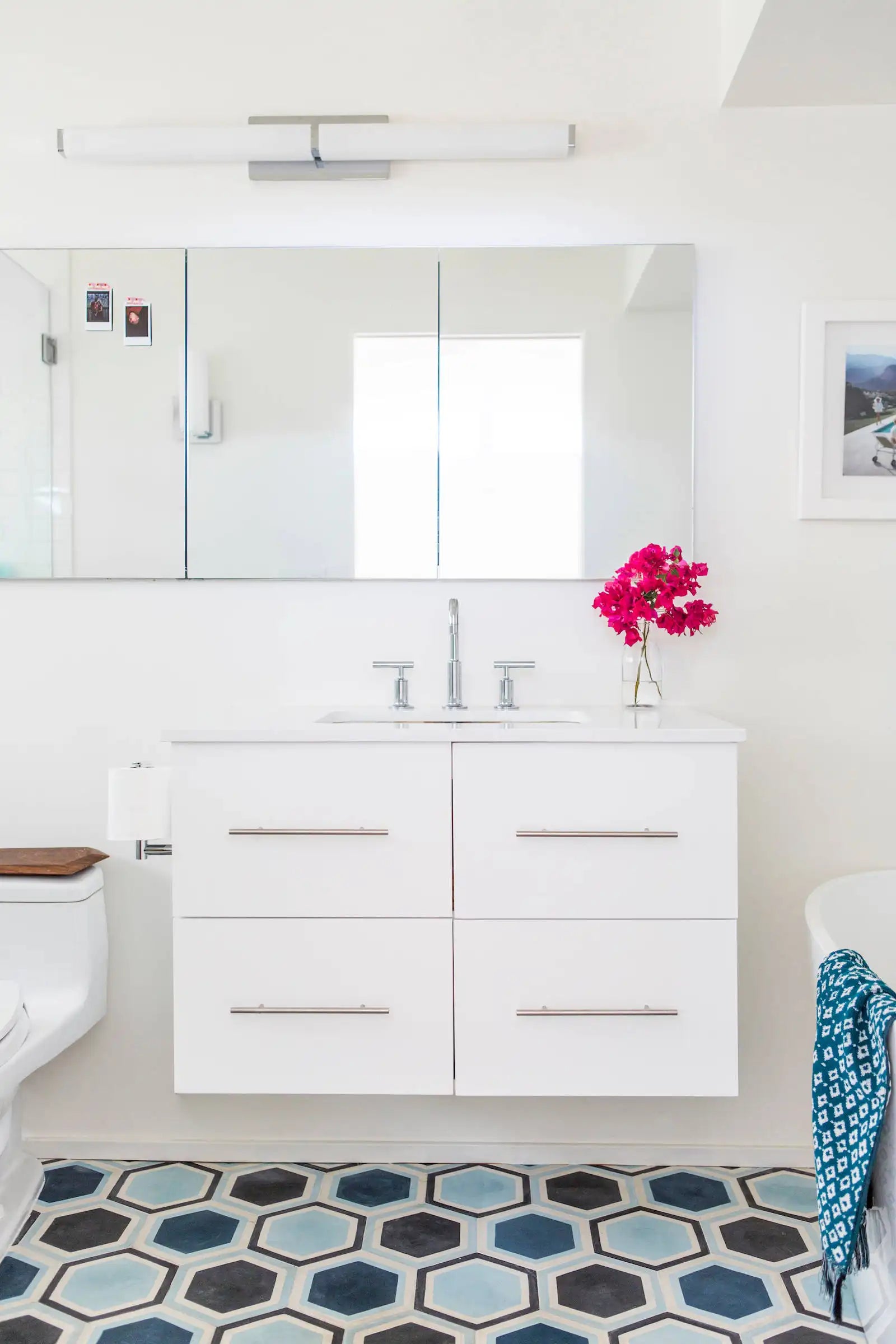 This bright bathroom features a clean, white recessed bathroom mirror cabinet above a floating vanity with colorful hexagonal floor tiles. | ACE DECOR