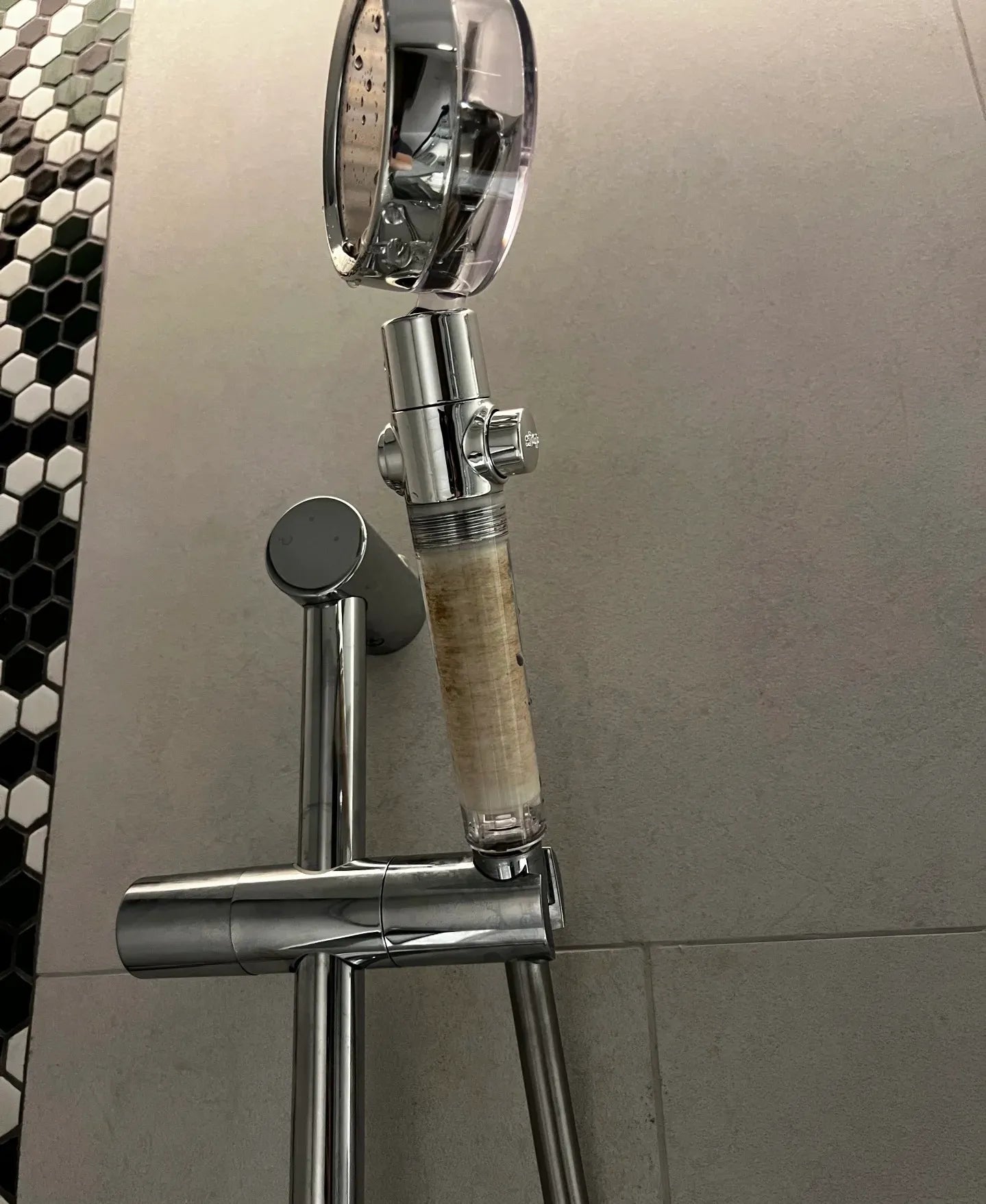 Modern shower head with integrated water softener filter for improved bathing experience.