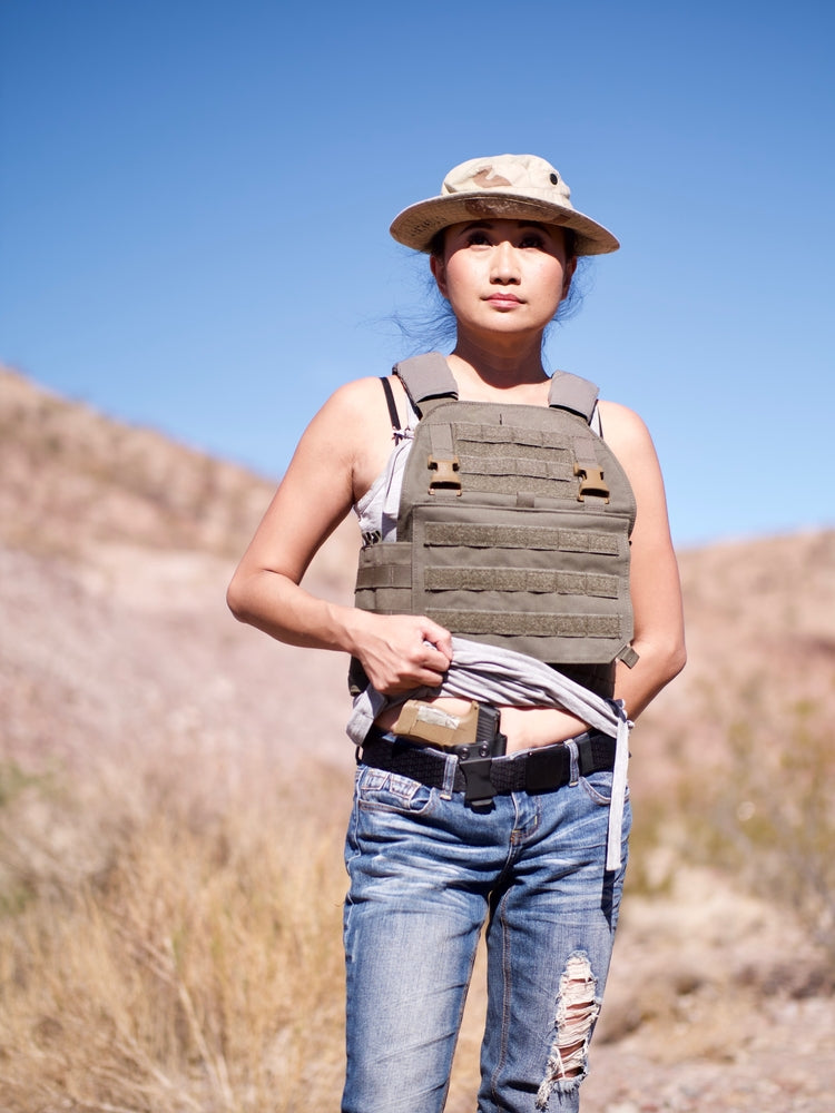 a woman stands lifting her shirt just above her navel revealing her appendix concealed carry