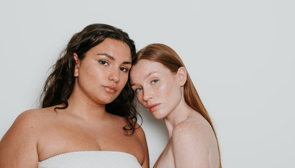 Dos chicas con tipos de piel distintos con una crema solar con color aplicada en la piel.