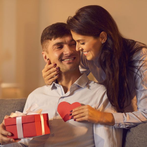Woman presenting a man with a 4 year anniversary gift and a heartfelt card