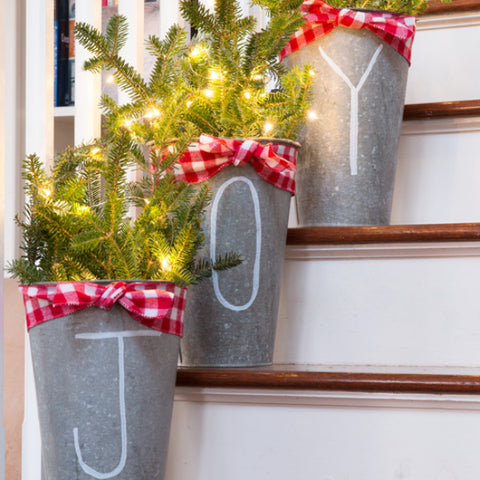 Festive christmas light decorations in galvanized buckets adorning each step of a home's staircase.