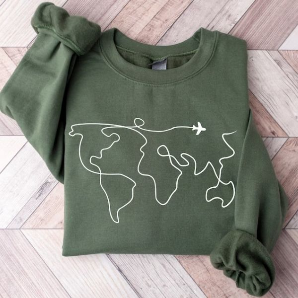 A green sweater with a minimalist line design of the world map and a plane, symbolizing adventure and travel.