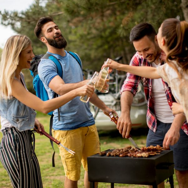 Friends laughing and enjoying a barbecue and grill party outdoors.