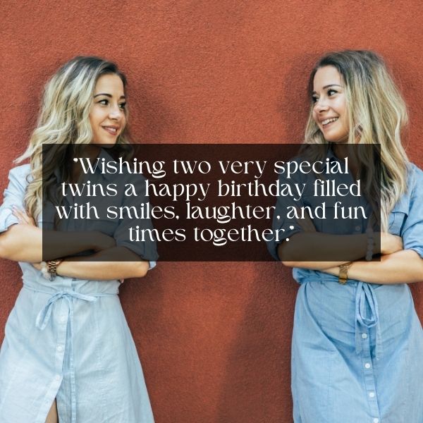 Two women in denim dresses leaning against a red wall with a birthday quote for twins.