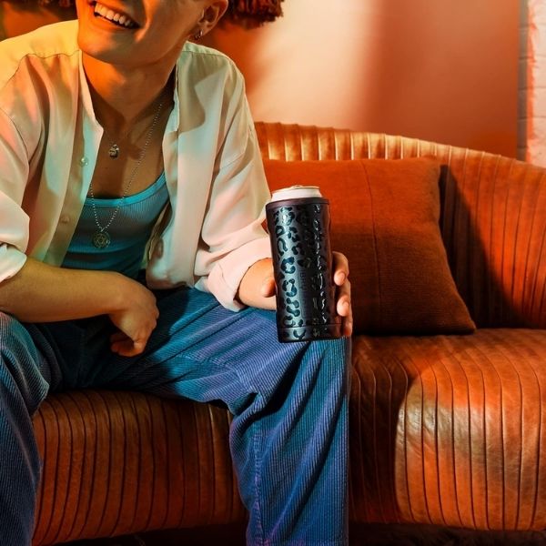 A person holding a stylish can cooler as a practical 21st birthday gift idea for beverage lovers.