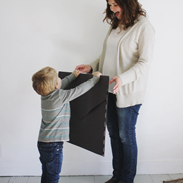 A child presenting a mother with a handmade oversized mothers day card idea.