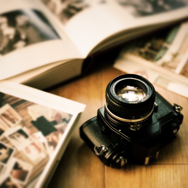 A vintage camera placed beside an open photo album, invoking nostalgia and the timeless art of photography.
