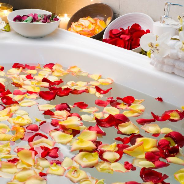 A luxurious bathroom setting exuding relaxation and romance with a bathtub filled with water and floating rose petals.