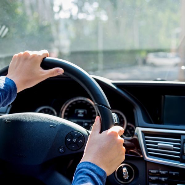 Hands gripping a steering wheel, suggesting focused driving and the freedom of traveling on an open road.