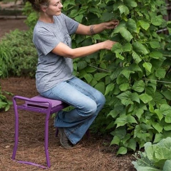 Woman comfortably using a purple Gardener's Supply Company garden kneeler and stool in her lush garden.