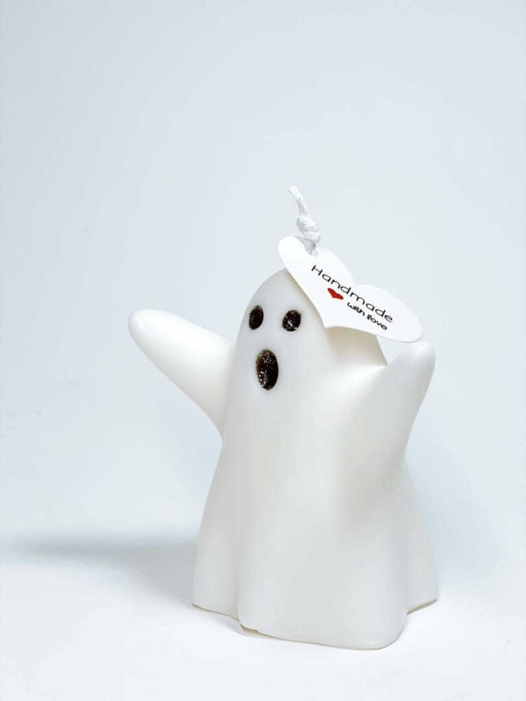 White ghost-shaped candle glowing in the dark