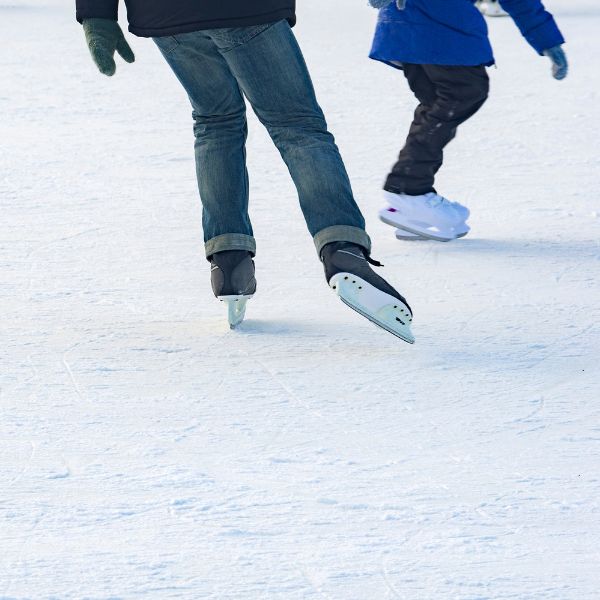 Adults ice skating together in an outdoor rink.