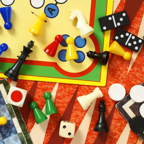 A colorful assortment of classic board games and pieces scattered on a table suggesting a fun and engaging family game night.