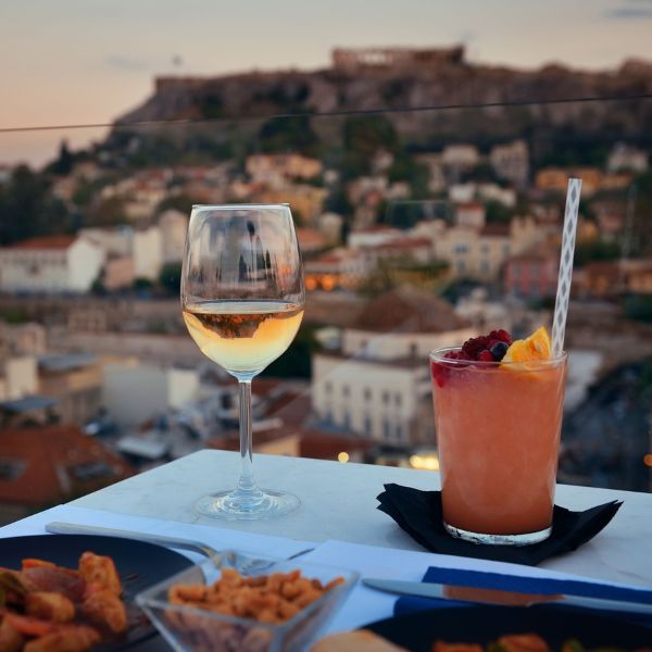 An elegant evening scene on a rooftop terrace with a glass of white wine and a cocktail accompanied.