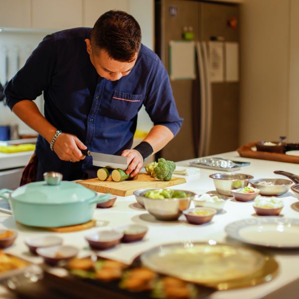 Chef preparing vegetables in a modern kitchen with various ingredients.