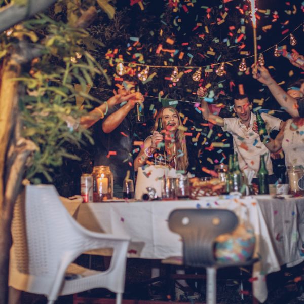 Joyful adults enjoying an outdoor celebration with confetti to illustrate fun adult birthday party ideas.