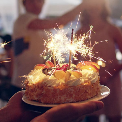 A sparkler-topped birthday cake being presented at an adult celebration to showcase birthday party ideas.