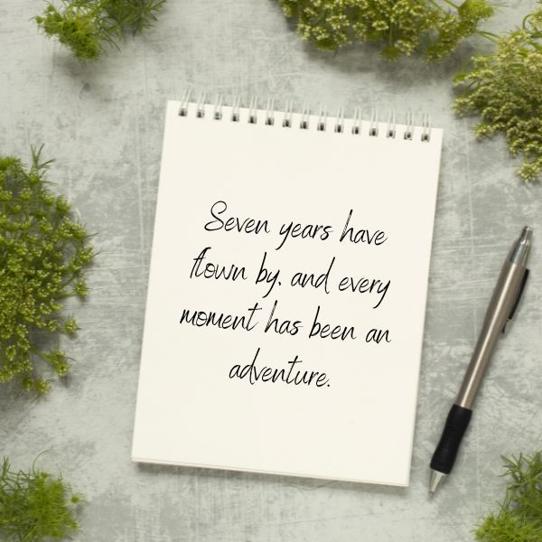 An open notebook with a reflective anniversary message, surrounded by a peaceful green setting.