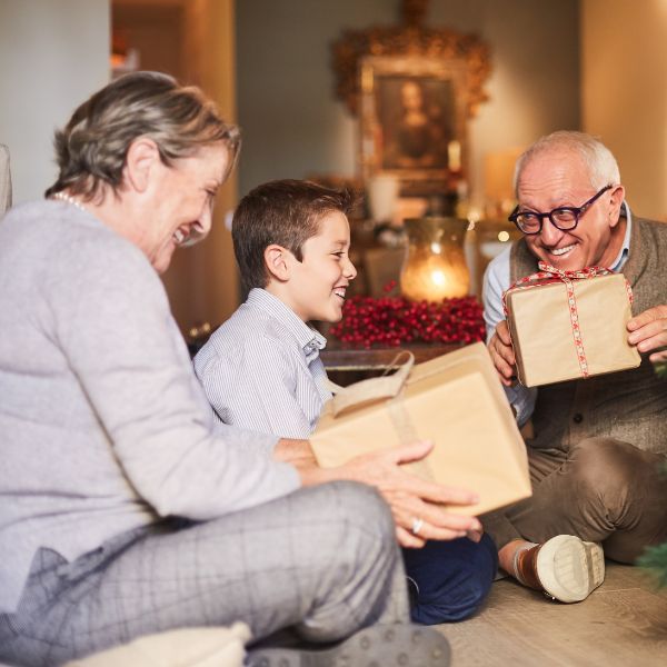 A joyful scene of grandparents receiving gifts from their grandchild, capturing the essence of giving on Grandparent's Day.