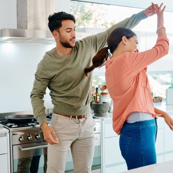 Happy couple dancing in the kitchen showcasing everyday love for her.