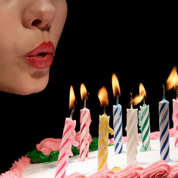 A beautifully decorated birthday cake with lit candles and colorful party decorations.