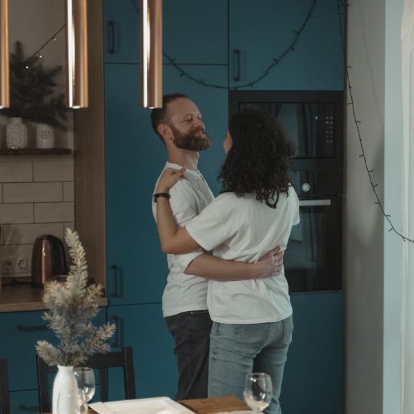 Couple embracing in a kitchen with blue cabinets and modern decor.