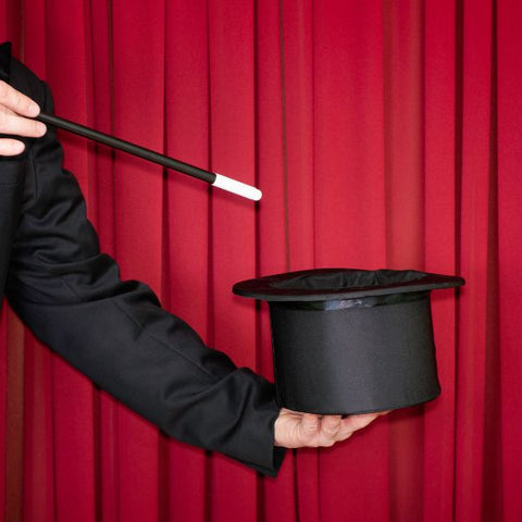 A magician's hand holding a top hat ready for a performance.
