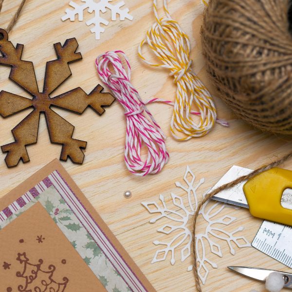 A variety of craft supplies including snowflake decorations and twine on a wooden surface, ready for a creative DIY project.