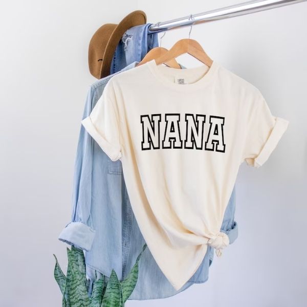 A casual 'NANA' printed tee displayed on a hanger, symbolizing a simple yet heartwarming gift for a grandmother.