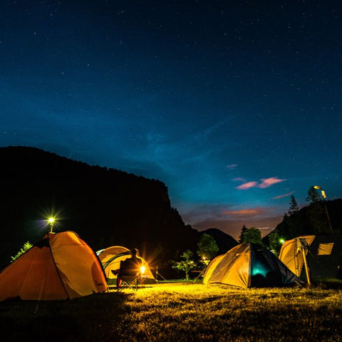 Tents illuminated under the night sky for a camping-themed adult birthday party.