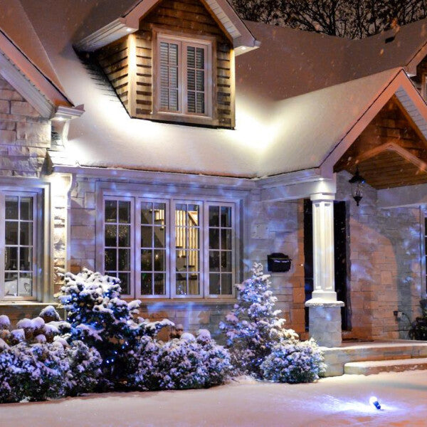 Innovative christmas light decorations using a projector display to illuminate a house with festive scenes.