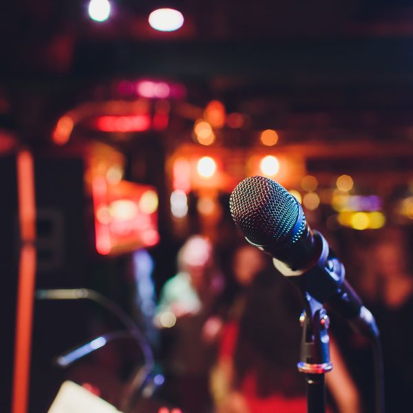 Close-up of a microphone on stage with blurred audience.