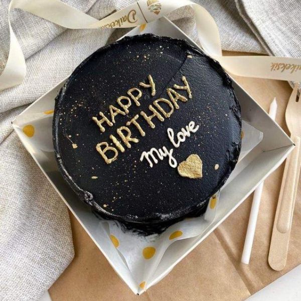 Elegant black birthday cake with golden lettering, loving message for boyfriend's birthday.