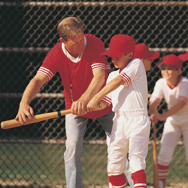 An image of a baseball coach that helps his juniors.