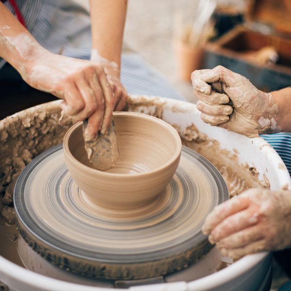 Hands molding clay on a potter's wheel, a couple shapes their love into tangible keepsakes.