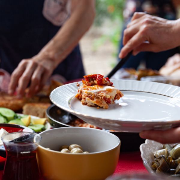 Serving a slice of lasagna at a themed potluck dinner.