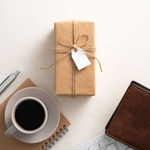 A person organizing their new workspace with a sleek pen, planner, and stylish coffee mug, showcasing practical and useful gifts.