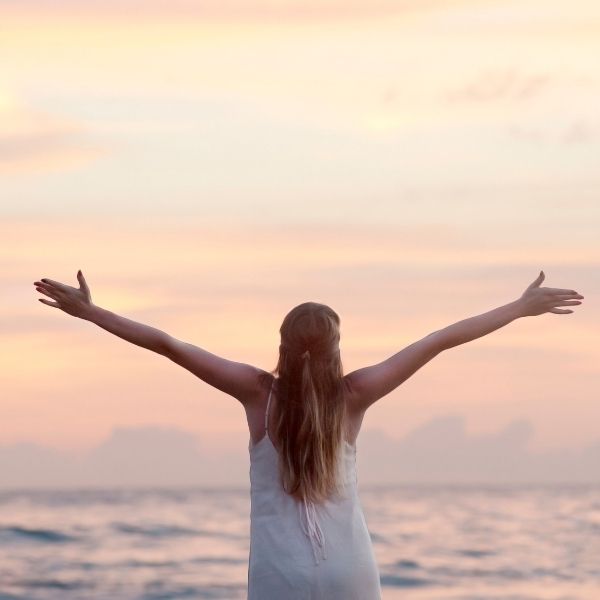 Image of a person with arms wide open facing the sunset.