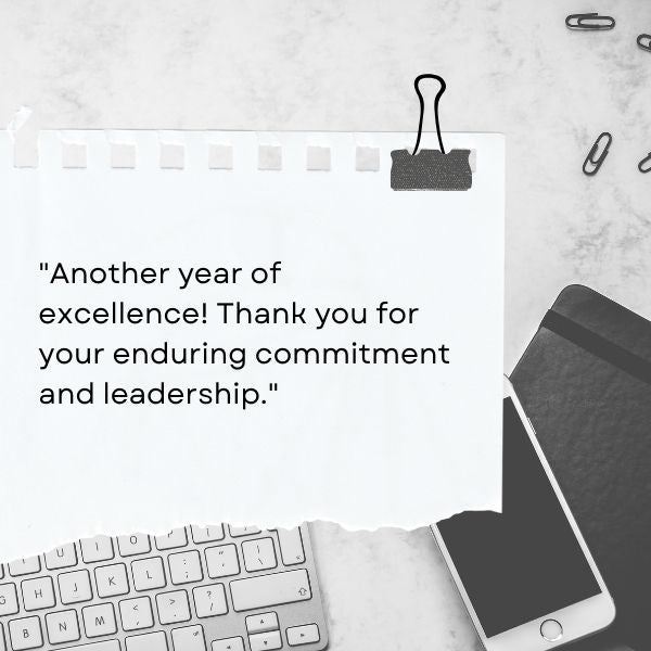 Note paper with a clip on a marble desk with 'Another year of excellence' work anniversary message