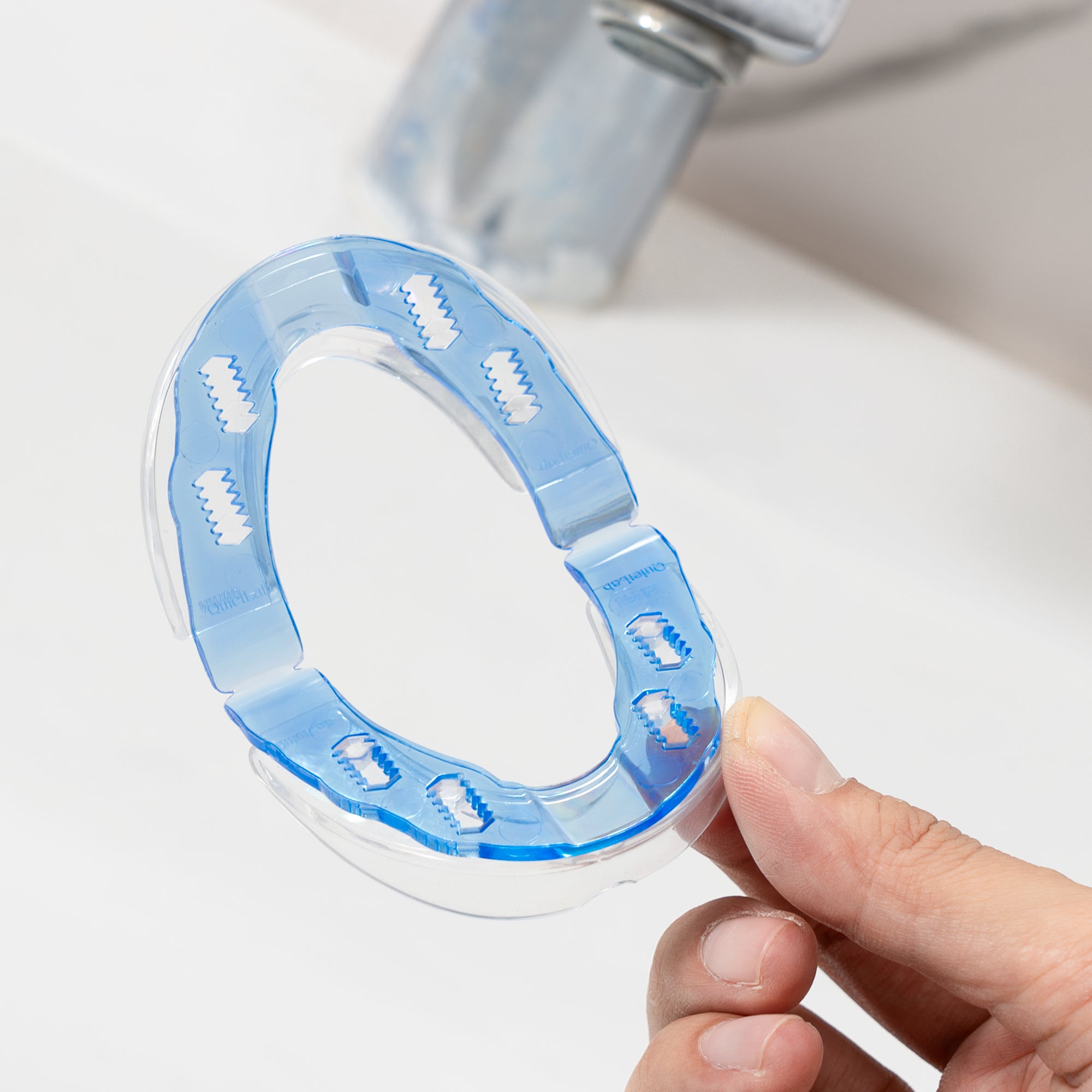 A person holding a blue plastic splash guard for a faucet.