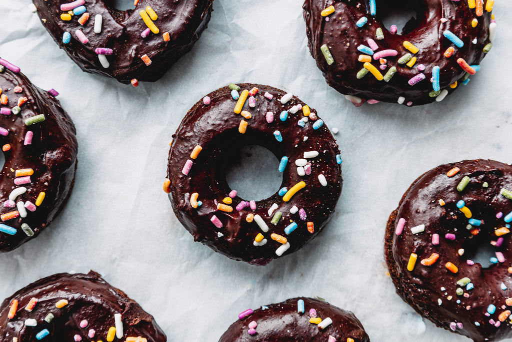 chocolate donuts with rainbow sprinkles from overhead on parchment paper